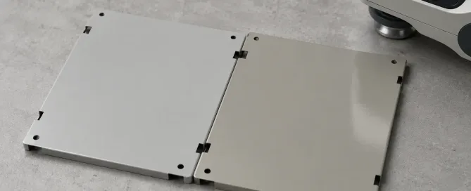 Zwei Blechplatten mit unterschiedlichen grauen Lacktönen nebeneinander platziert, die eine sichtbare Farbabweichung zeigen
